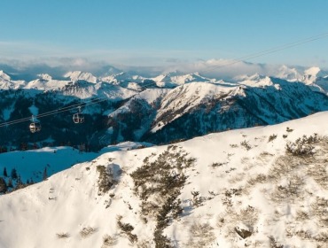 Kolejki linowe suną nad ośnieżonymi górami w Wagrain-Kleinarl pod czystym, błękitnym niebem i odległymi szczytami.