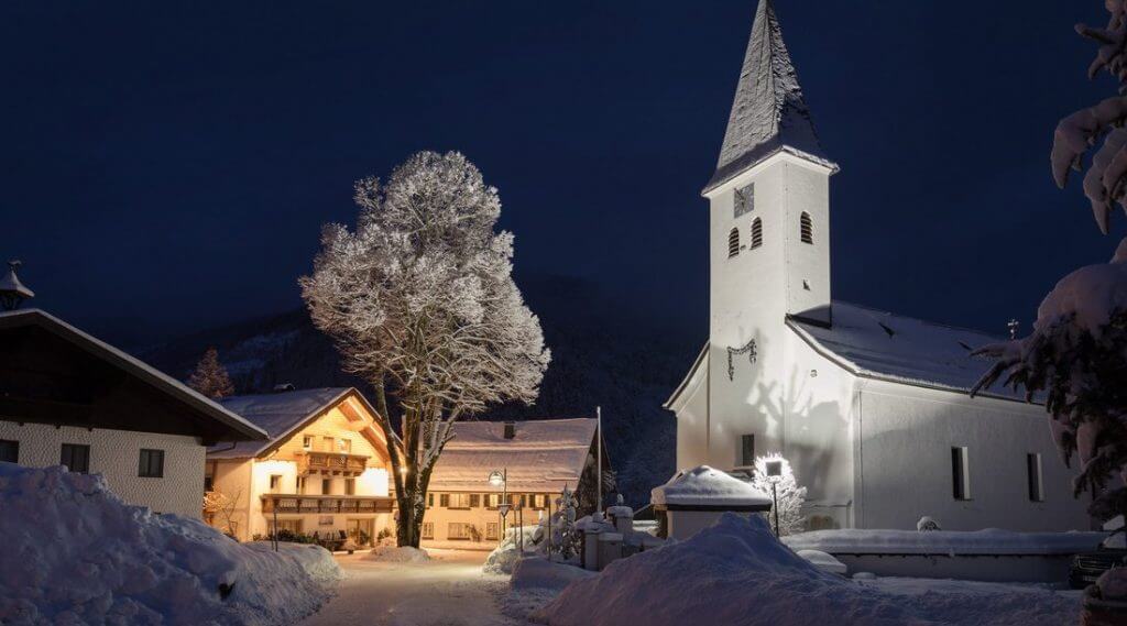 Zimowy krajobraz z kościołem i wieskimi domostwami w Hintersee, gdzie Joseph Mohr przez 11 lat prowadził samodzielnie swoją pierwszą parafię.