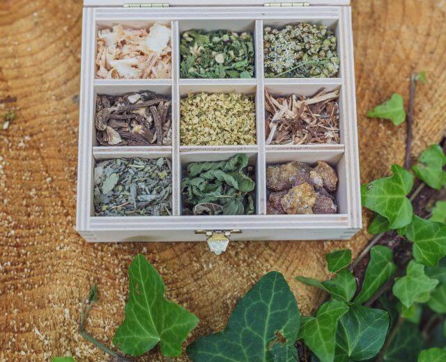 Drewniane pudełko z dziewięcioma przegródkami na suszone zioła i żywice, inspirowane Tradycyjną Medycyną Europejską.