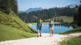Dwie osoby cieszą się turystyką pieszą na żwirowej ścieżce w pobliżu jeziora Dachstein West, wzgórz i widoków na góry.