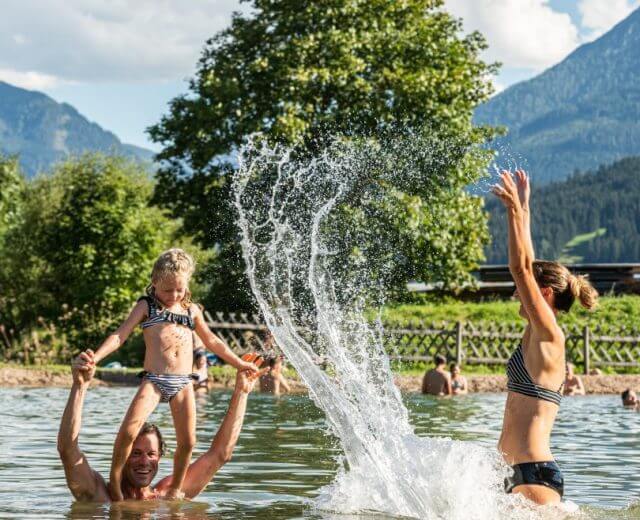 spass_fuer_die_ganze_familie_am_badesee_ebensalzburger_sportwelt_lorenz_masser-1170×658 Rodzina z dziećmi bawi się w wodzie na kąpielisku w Ebensee, w Salzburskim Siwecie Sportu.
