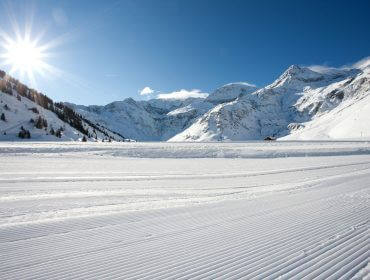 Świeżo przygotowane stoki narciarskie dla zrównoważonego rozwoju narty pod zaśnieżonymi górami i czystym błękitnym niebem.