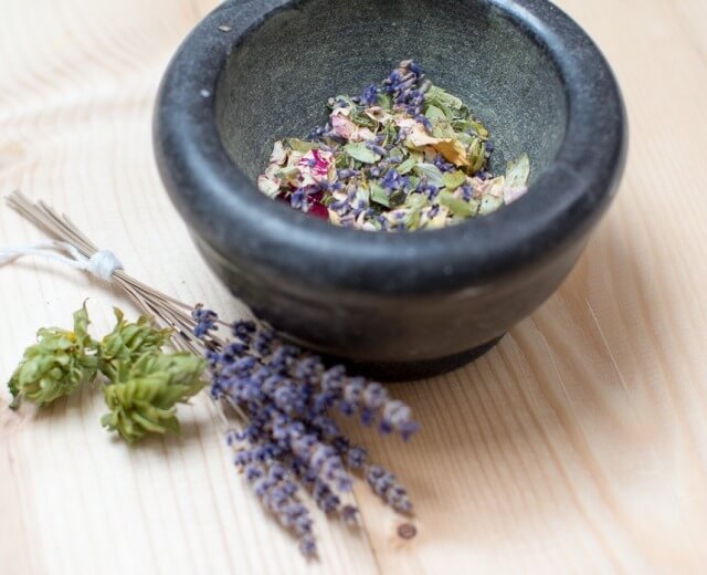 Kamienna misa z suszonymi ziołami, herbata ziołowa na jesień zimę i wiązka lawendy na drewnie.