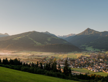 Małe miasteczko w zielonej dolinie, Altenmarkt-Zauchensee, leży pod górami pod czystym niebem o wschodzie słońca.