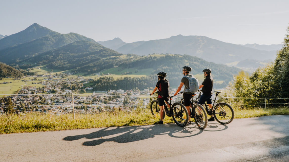 Trójka rowerzystów robi przerwę na trasie, aby podziwiać widok z góry na miasteczko Altenmarkt.