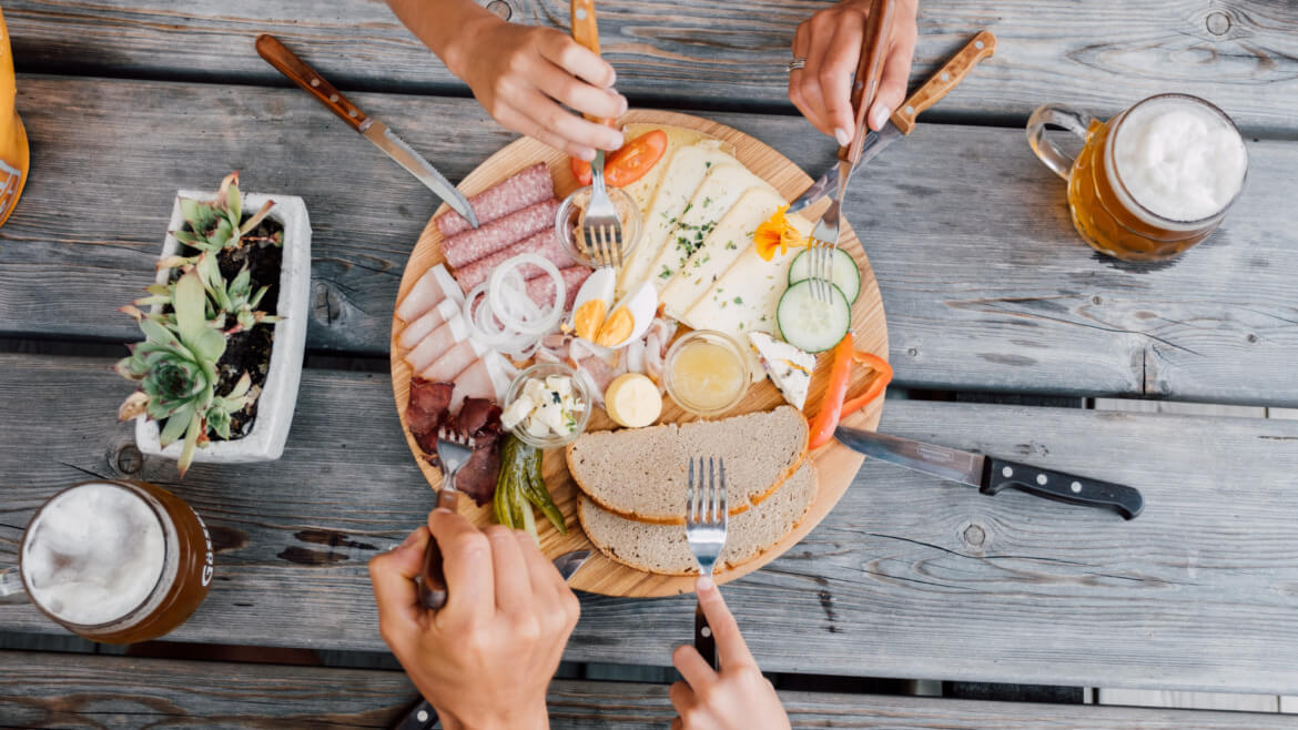 Tradycyjna deska z przysmakami - boczkiem, serem, chlebem razowym, jajkiem i świeżymi warzywami.