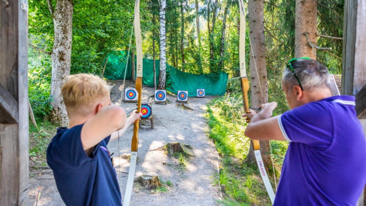 Dwie osoby cieszą się strzelaniem z łuku, celując do kolorowych tarcz we Flachau - sport pełen zabawy i adrenaliny. (Powiększony widok)