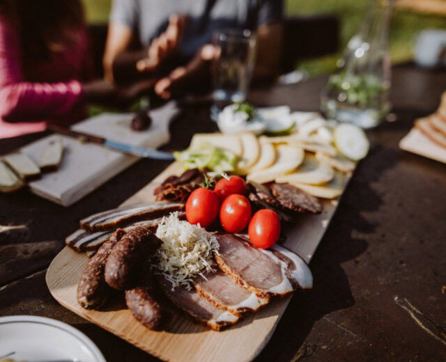 Deska wędlin z mięsami, serami i pieczywem świętuje sezon na pomidory na stole na świeżym powietrzu z przyjaciółmi.