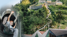 Chłopiec zjeżdża ze zjeżdżalni tunelowej na zboczu wzgórza w pobliżu fortu Kniepass i nowoczesnej szklanej konstrukcji.