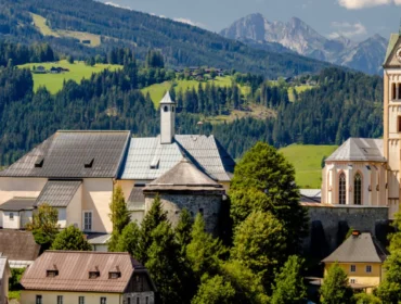 Małe europejskie miasteczko z kościołem i górami, oddające urok lata w Radstadt w słoneczny dzień.