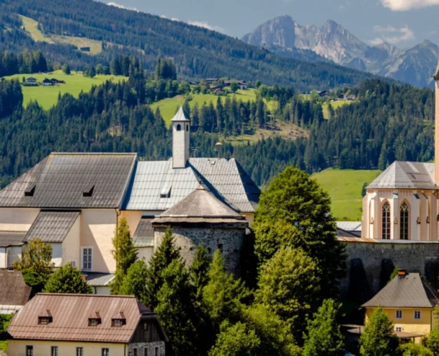 Małe europejskie miasteczko z kościołem i górami, oddające urok lata w Radstadt w słoneczny dzień.