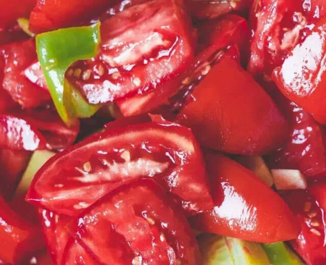 Zbliżenie na pokrojone czerwone pomidory i zieloną paprykę, idealne składniki świeżego gazpacho.