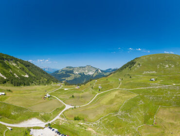 Widok z lotu ptaka na zielone wzgórza Tennengau i kręte drogi pod czystym, błękitnym niebem w górskim krajobrazie.
