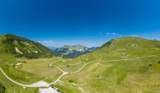 54564875479_0a0d53e95a_b Widok z lotu ptaka na zielone wzgórza Tennengau i kręte drogi pod czystym, błękitnym niebem w górskim krajobrazie.
