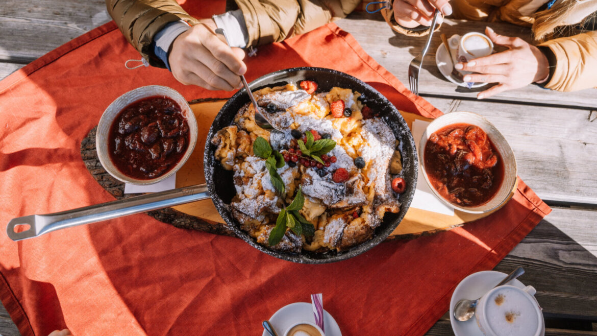Patelnia Kaiserschmarrn z jagodami we Flachau poza stokami, dzielona przez przyjaciół przy stole. (Powiększony widok)